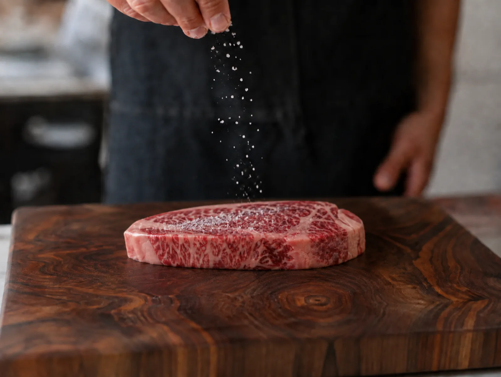 Ein Kangen Wagyu Ribeye wird auf einem Walnussholzbrett gewürzt